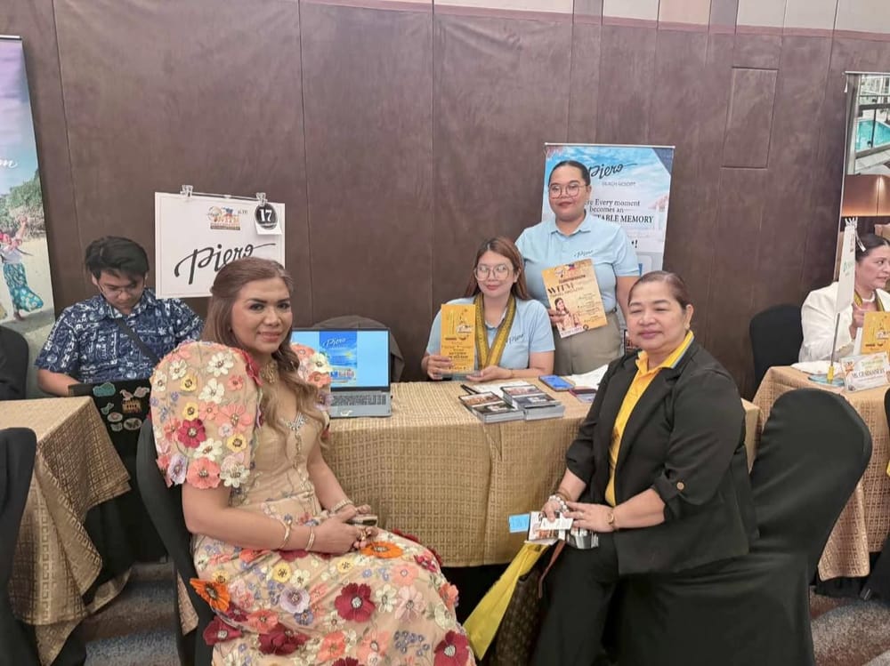Four Piero Beach Resort staff from Boracay at their exhibitor table with the WITM magazine, a laptop and stacks of brochures.
