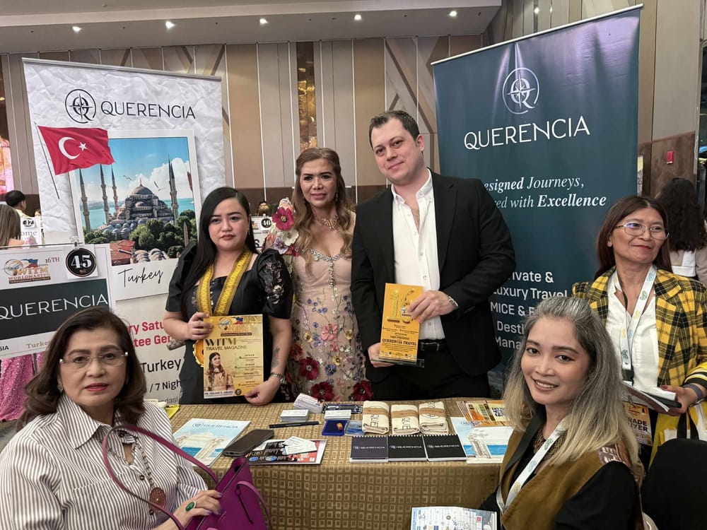 A Querencia Travel seller from Turkey holding a 16th WITM certificate of recognition, the Turkish flag and a Blue Mosque banner behind the booth.