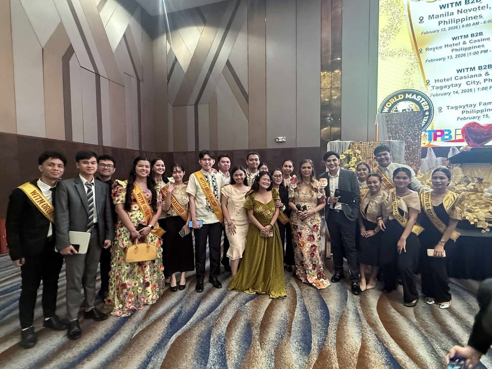 The WITM organizing team in terno gowns and barong with gold WITM organizer sashes, posed before the 16th-edition schedule screen.